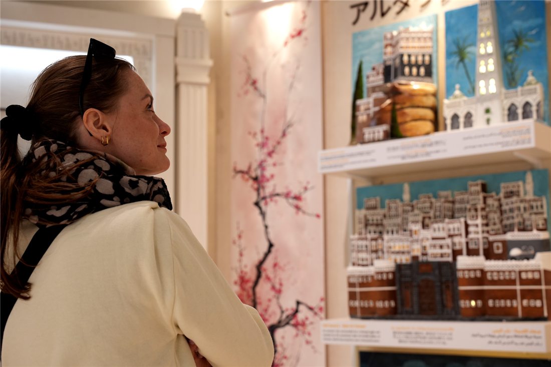 زائرة تتعرف على جناح القرية اليمنية — A visitor exploring the Yemeni Village pavilion